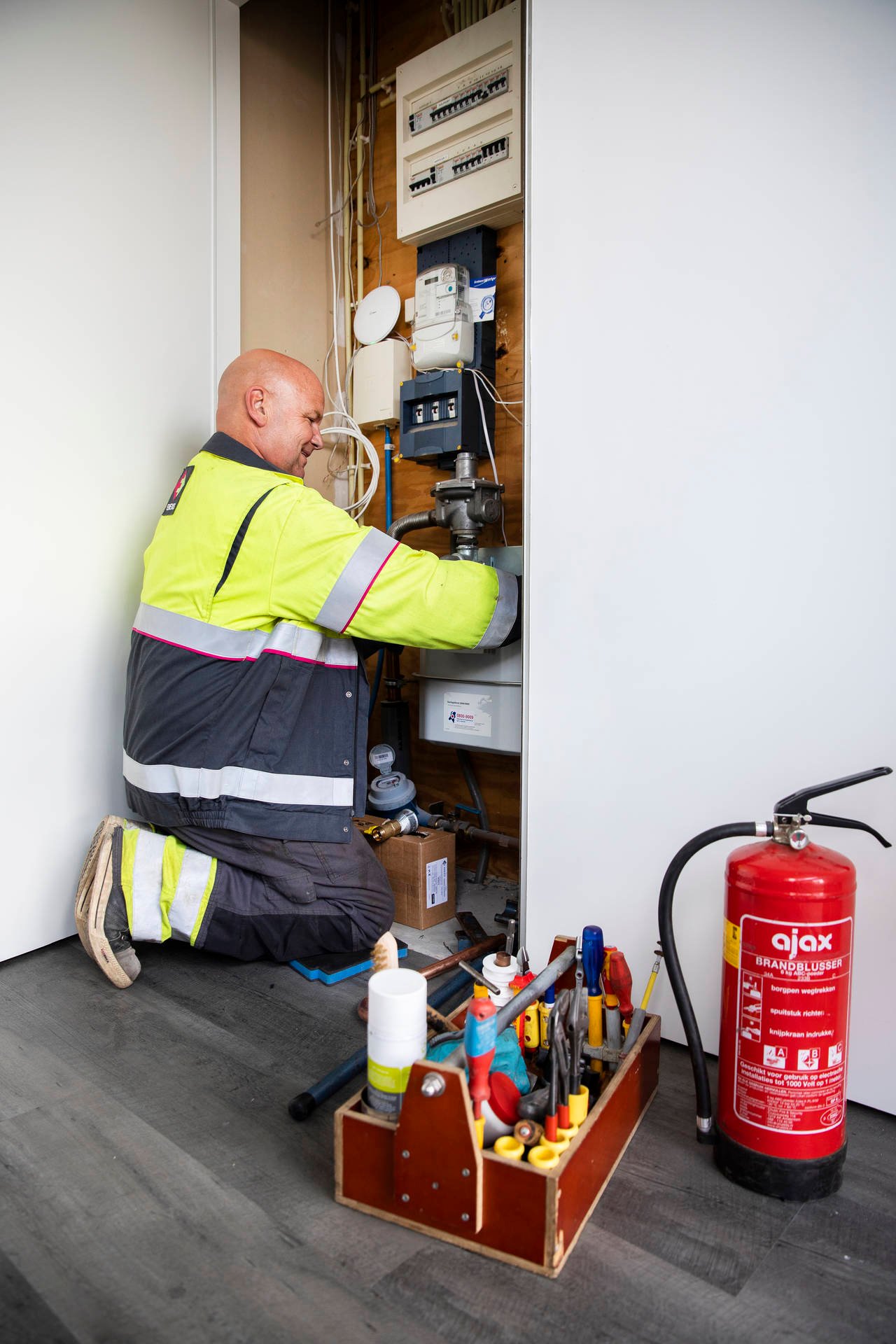 Monteur van Enexis geknield bij meterkast voor controle