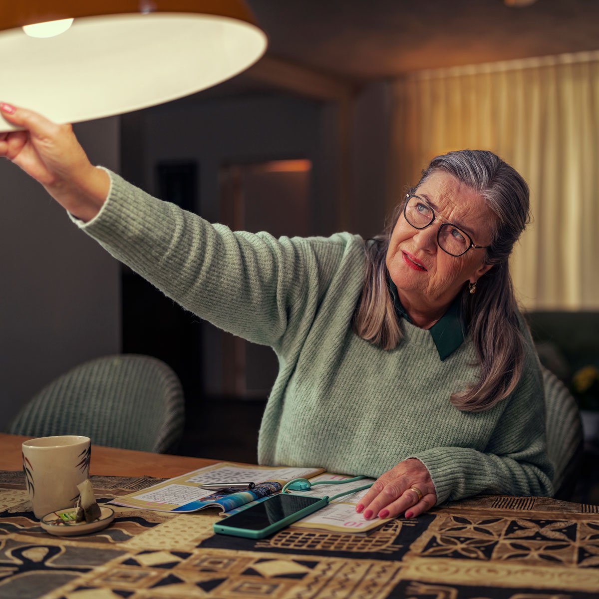 Maaike aan tafel met haar handen aan de lamp