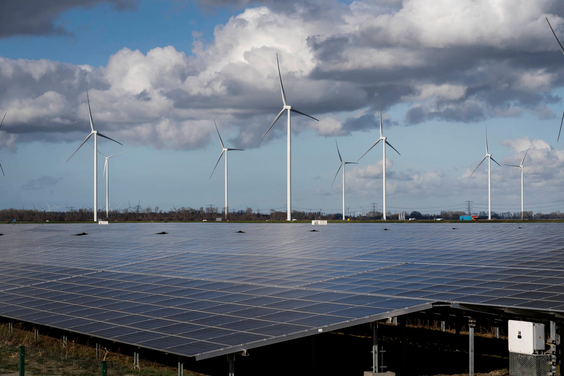 Zonnepanelen met windmolens op de achtergrond