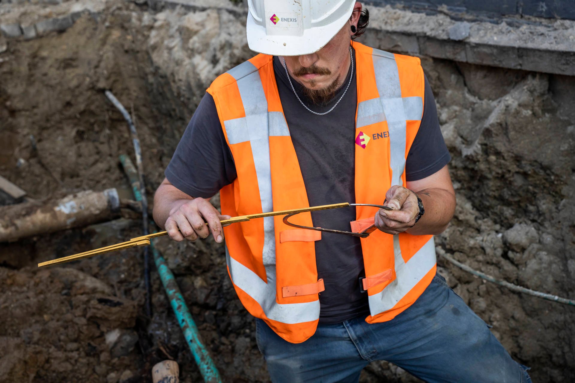 Monteur van Enexis aan het werk in kuil met kabel