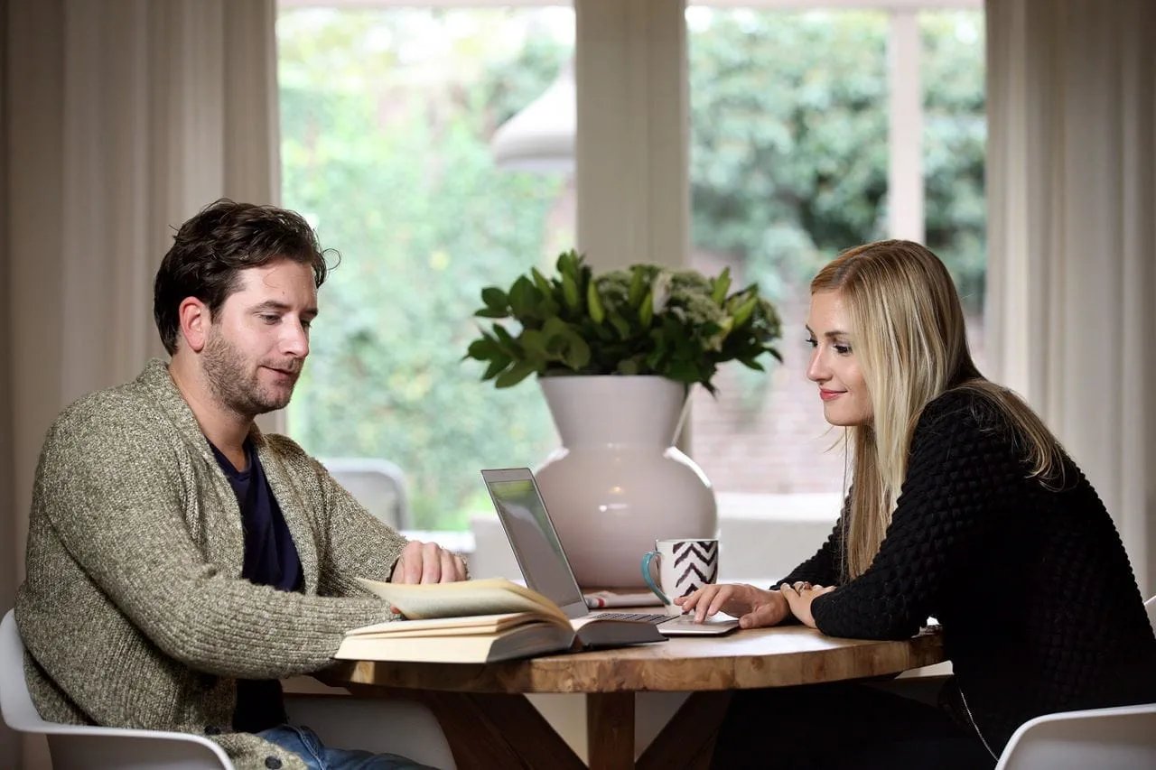 Stel aan tafel met laptop en boek